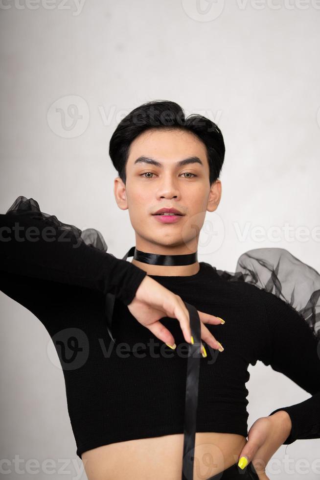 un hombre transgénero posa con un vestido negro con una cara elegante y cabello negro foto