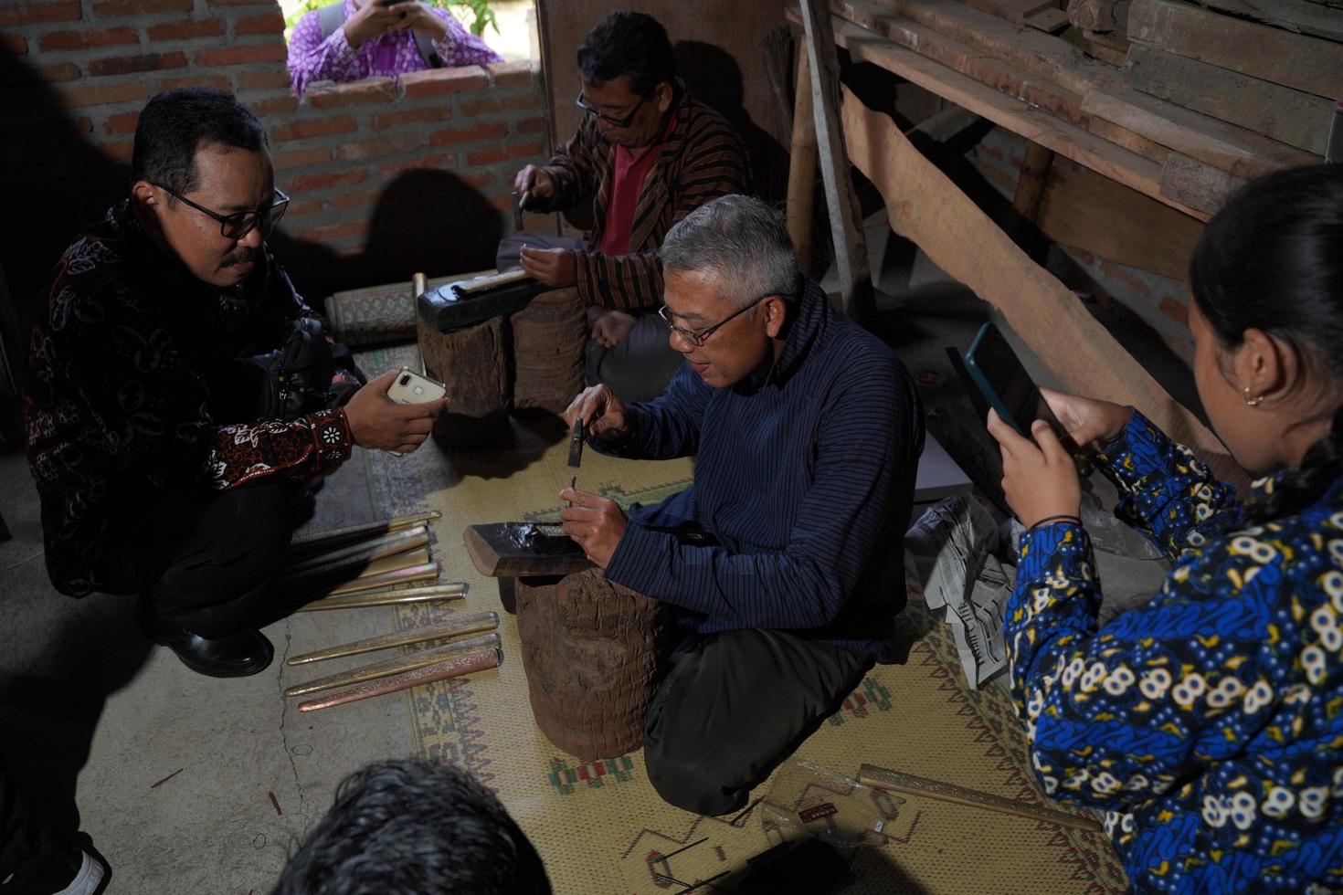 Los artesanos de keris están enseñando a los visitantes sobre el proceso de elaboración de keris en el taller. bantul, indonesia - 25 agosto 2022 foto