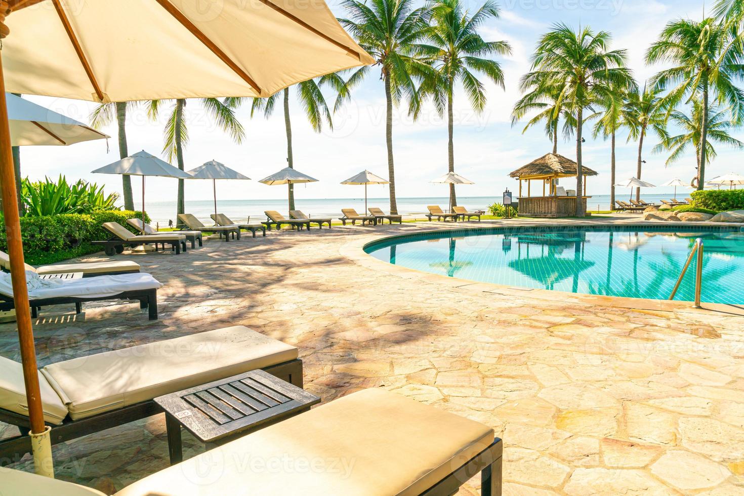 Hermosa sombrilla y silla alrededor de la piscina en el hotel y resort foto