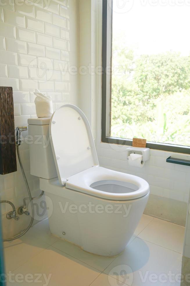 white toilet in restroom with window photo