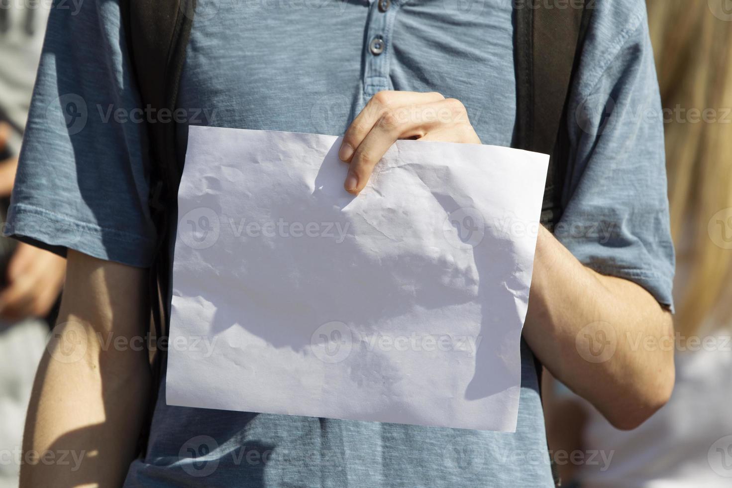 Man's hands hold a blank white sheet of paper. photo