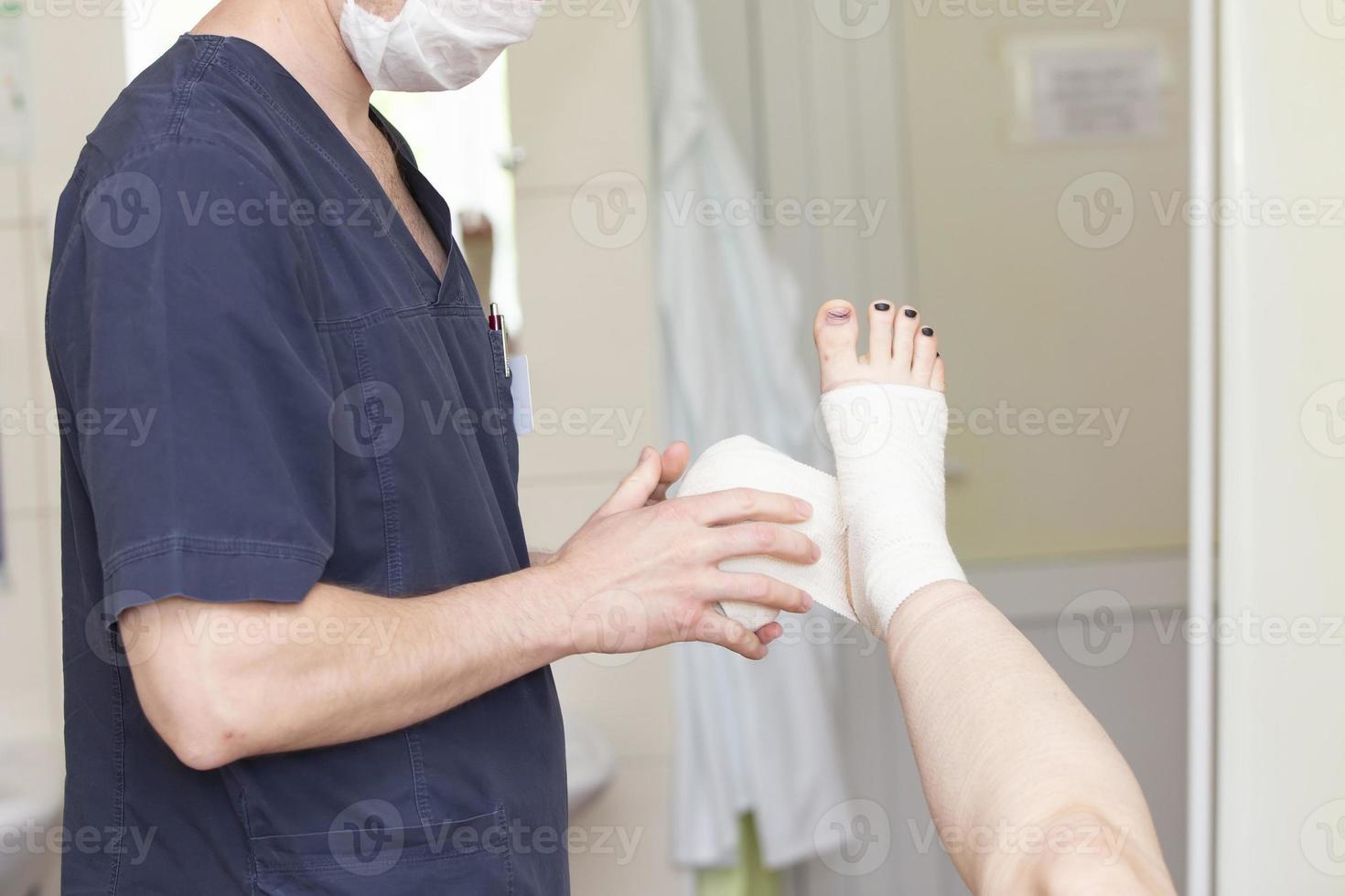 The doctor bandages the patient's leg. Surgeon and patient after vein surgery. photo