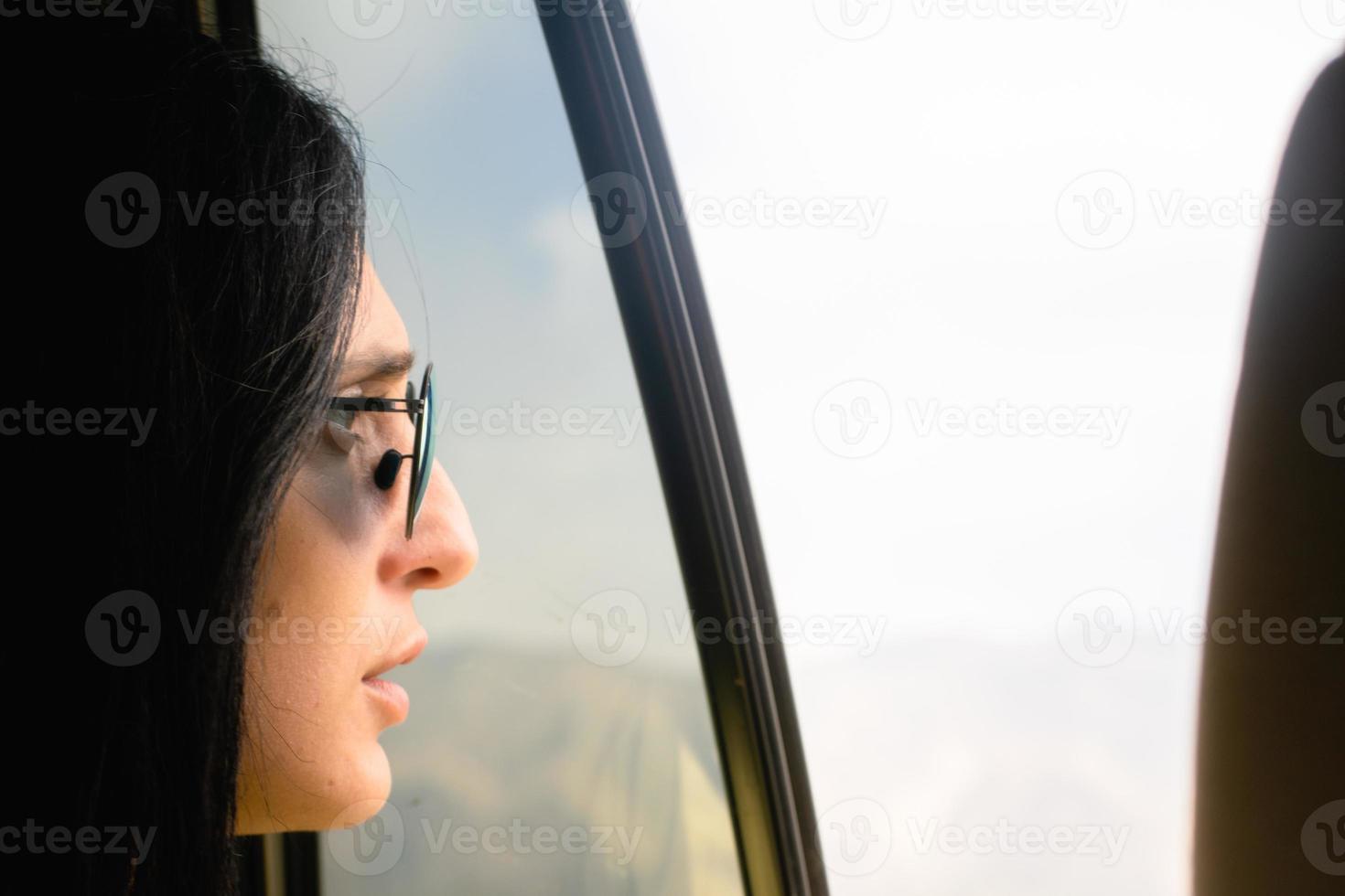 Young petty caucasian woman face with glasses stare surprised from car window to right side nature empty space photo