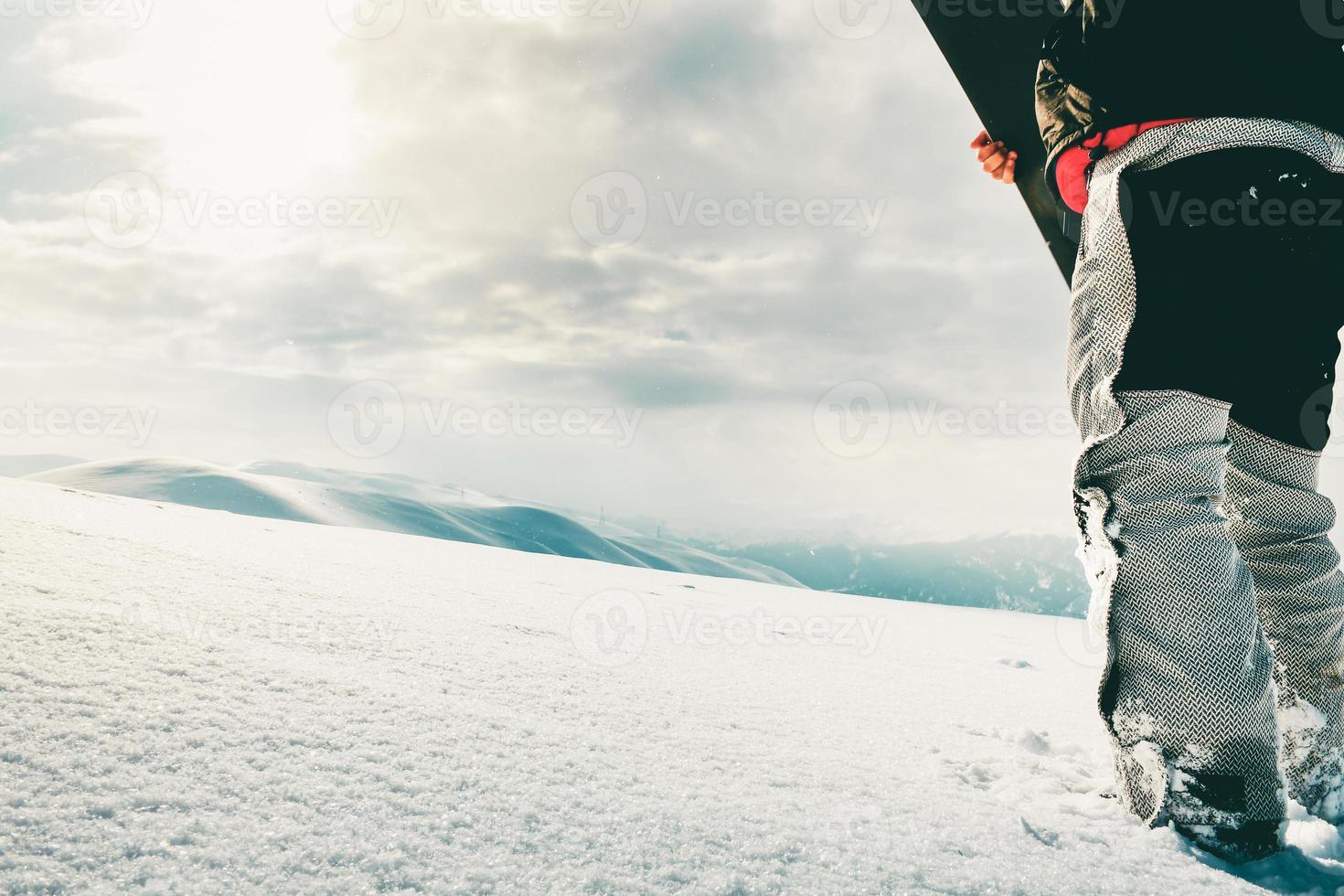Snowboarder dressed in a full protective gear for extreme freeride snowboarding posing with a snowboard walking. Isolated on gray white snow background. photo