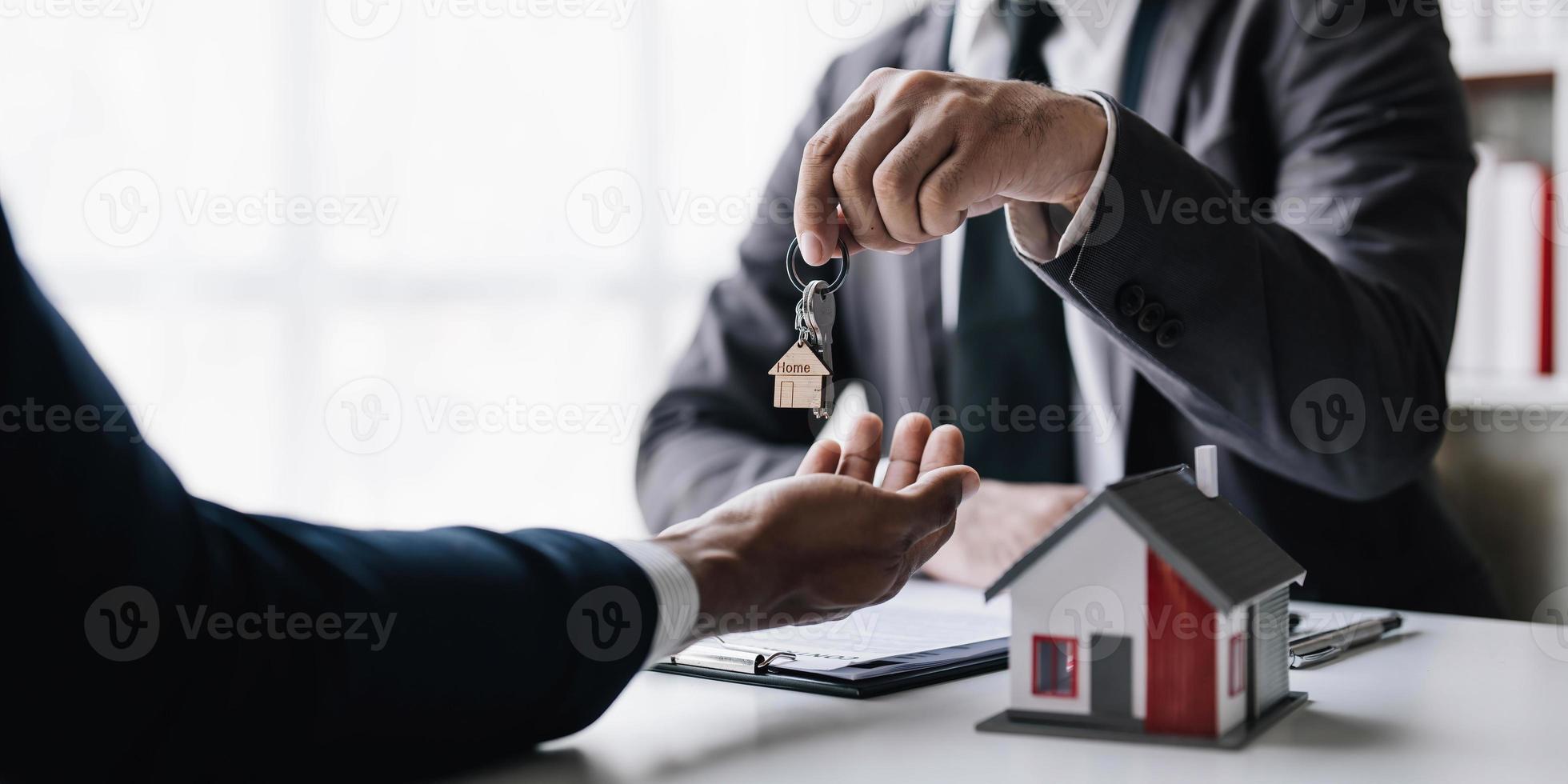 Real estate agents agree to buy a home and give keys to clients at their agency's offices. Concept agreement photo