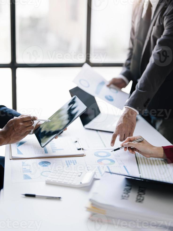 gente de negocios reunida usando computadora portátil, calculadora, cuaderno, papel gráfico del mercado de valores para planes de análisis para mejorar la calidad el próximo mes. conferencia discusión concepto corporativo. foto