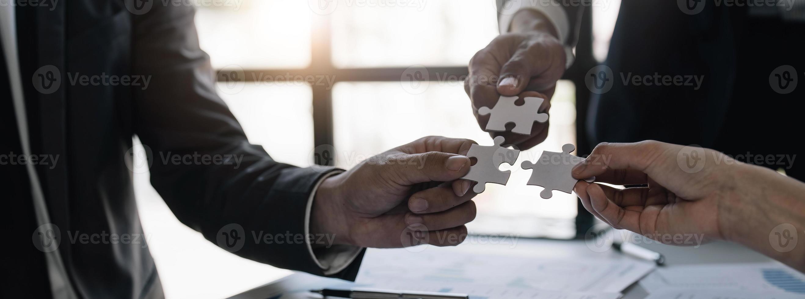 A group of business people assembling jigsaw puzzle. The concept of cooperation, teamwork, help and support in business. photo
