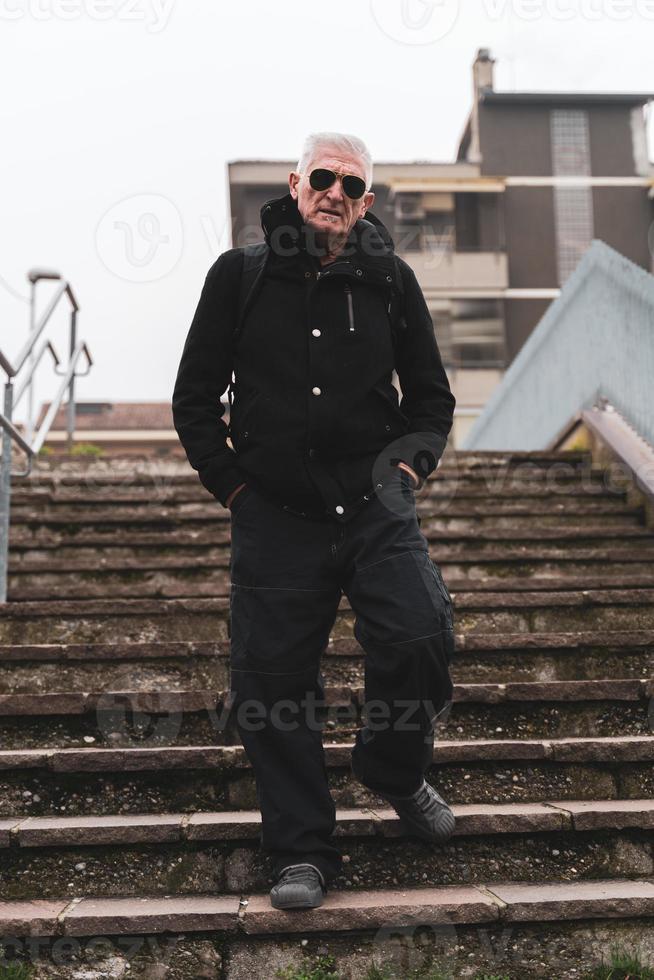 mature man rap singer posing on stairs outdoors on the outskirts of a city photo