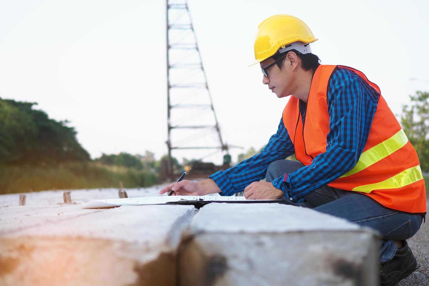 los ingenieros están leyendo el plano que se coloca sobre pilotes en el área de construcción y la parte posterior tiene grúas. concepto de contratista de construcción foto