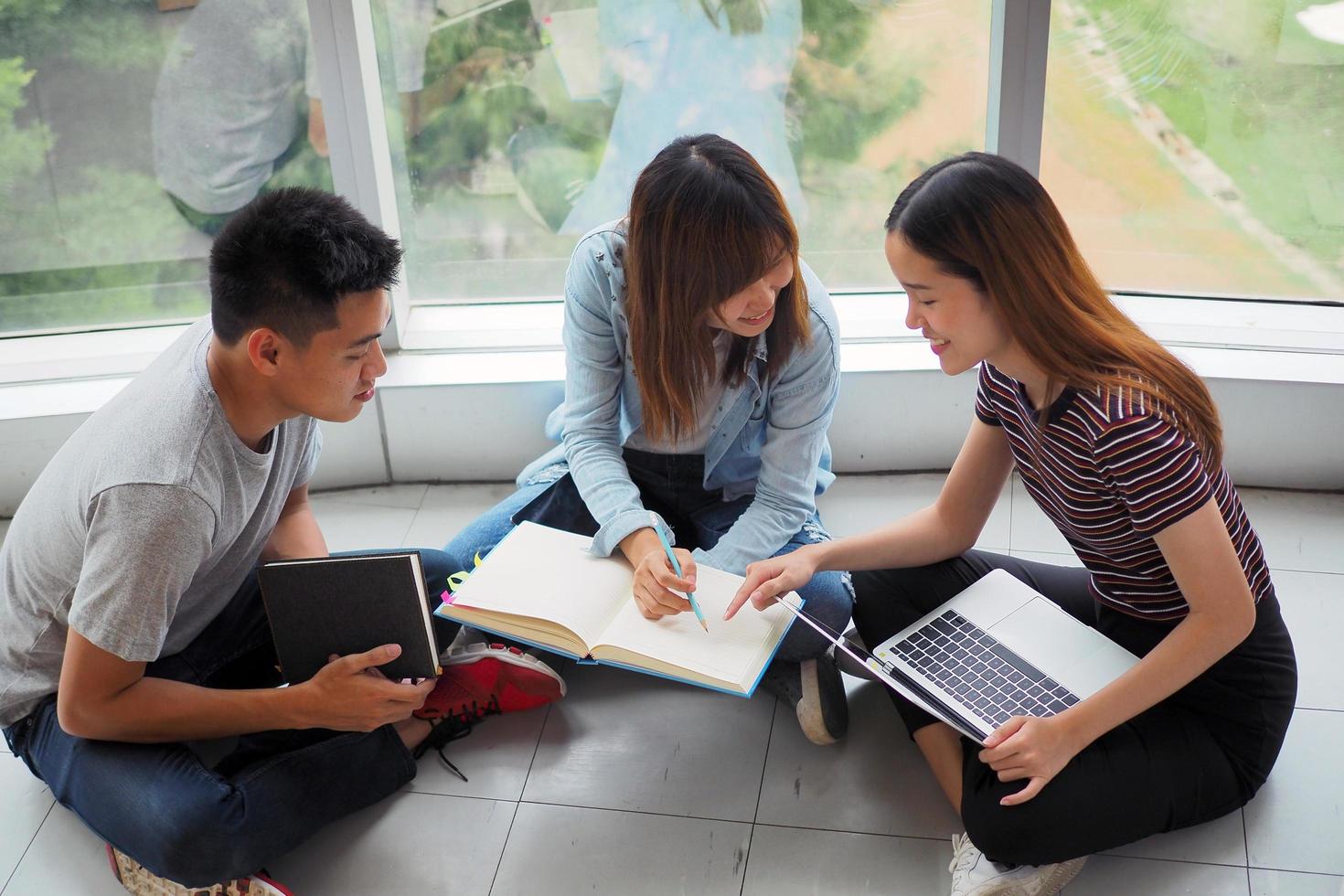 Student groups are viewing information in books and laptops. There is a gesture of agreement and a smile, happy to learn together. photo