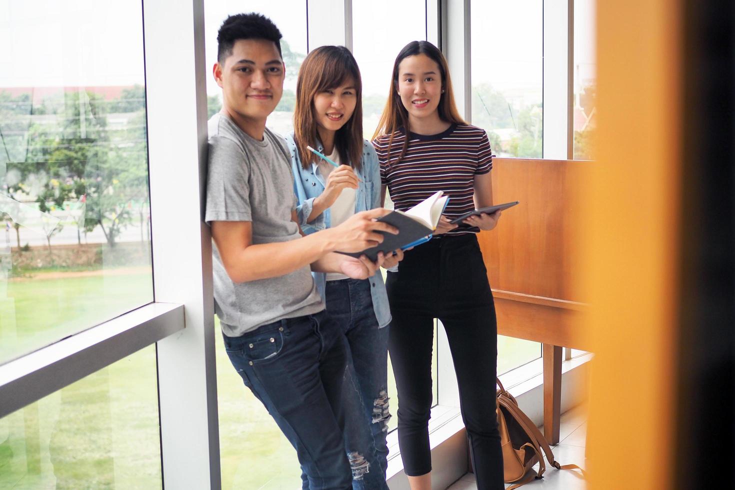 los grupos de estudiantes están viendo información en libros y computadoras portátiles. hay un gesto de acuerdo y una sonrisa, felices de aprender juntos. foto