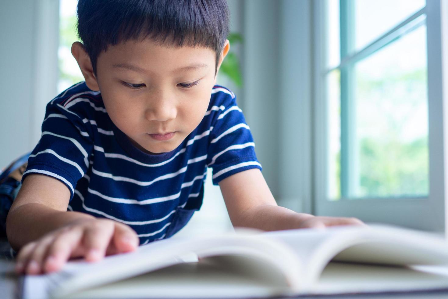 The little boy is reading a book in the house area. Learning at home photo