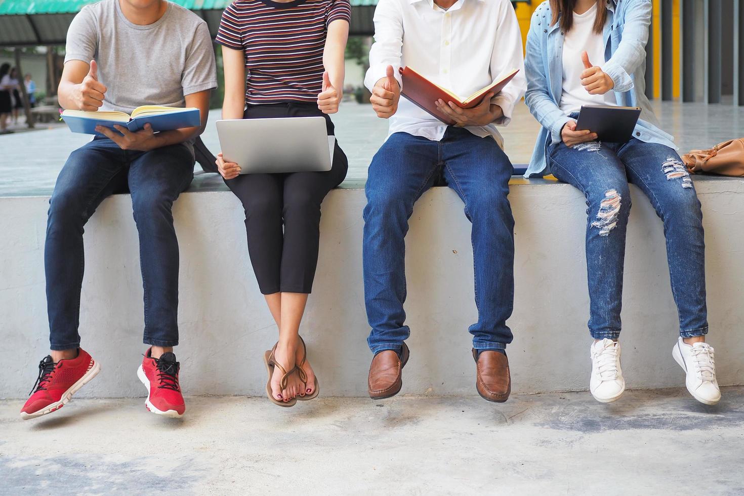 los jóvenes se sientan en filas alineadas leyendo libros usando computadoras portátiles y teléfonos inteligentes. agruparse para el entretenimiento y el conocimiento. foto