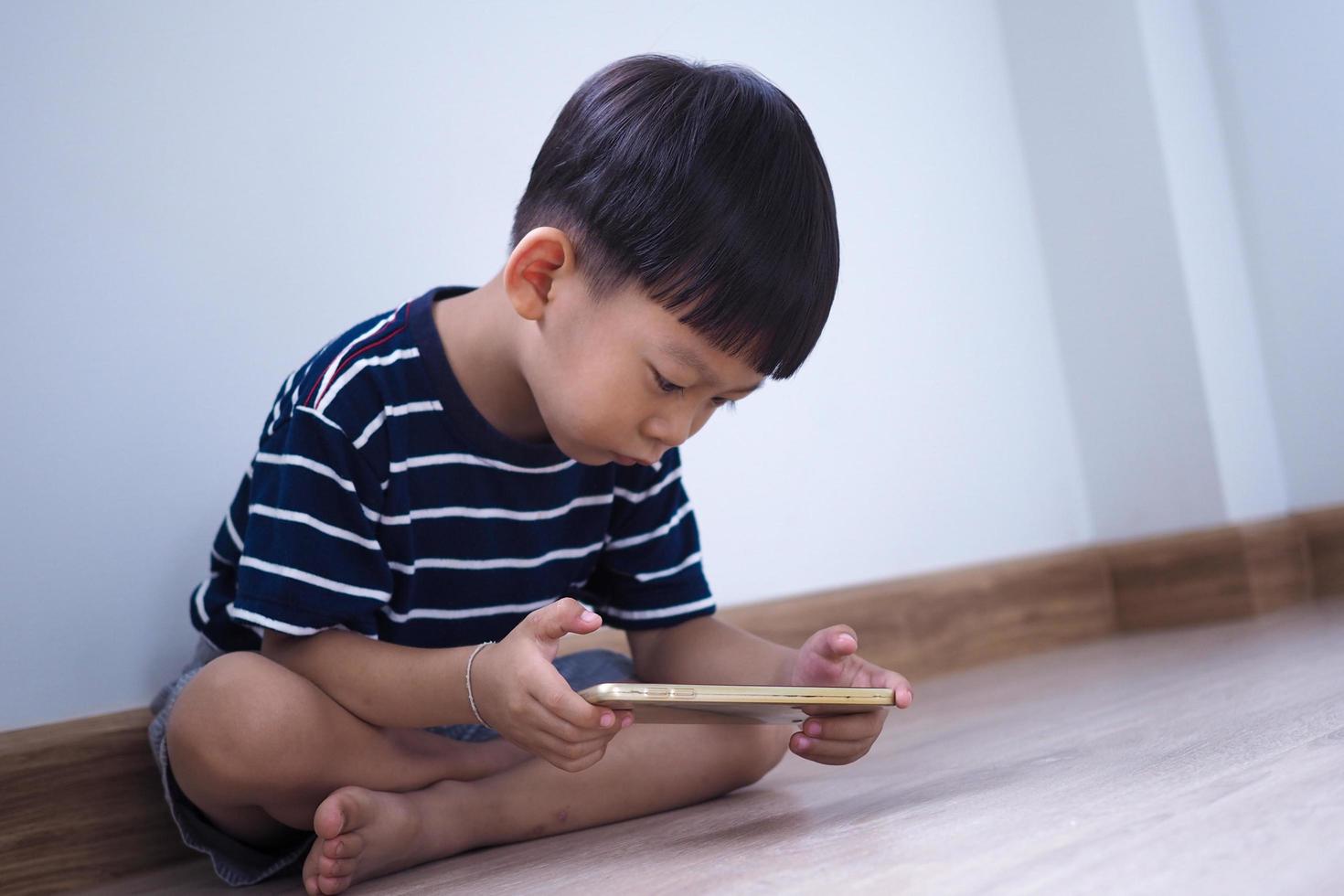 niños asiáticos en la era de las redes sociales que se enfocan en teléfonos o tabletas. no se preocupan por el entorno que los rodea y tienen problemas en los ojos. foto