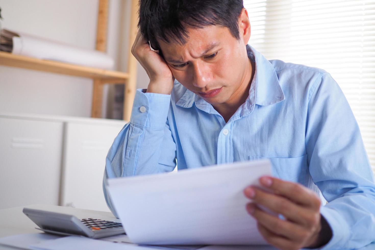 Business men are worried about the documents or bills they hold in their hands. Stressed with the burden of home expenses photo