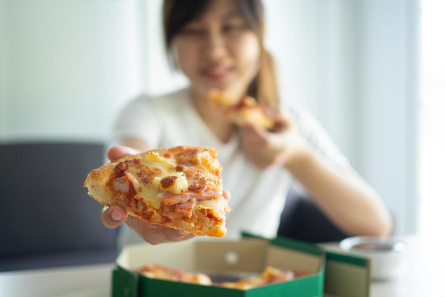 Hungry woman enjoys eating Hawaiian pizza after order online to eat at home. happy and relaxed to eat concept photo