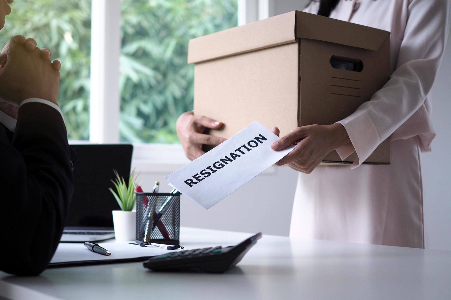 A female businessman holding a brown cardboard box and sends a resignation letter to the management. Moving jobs and vacancies photo