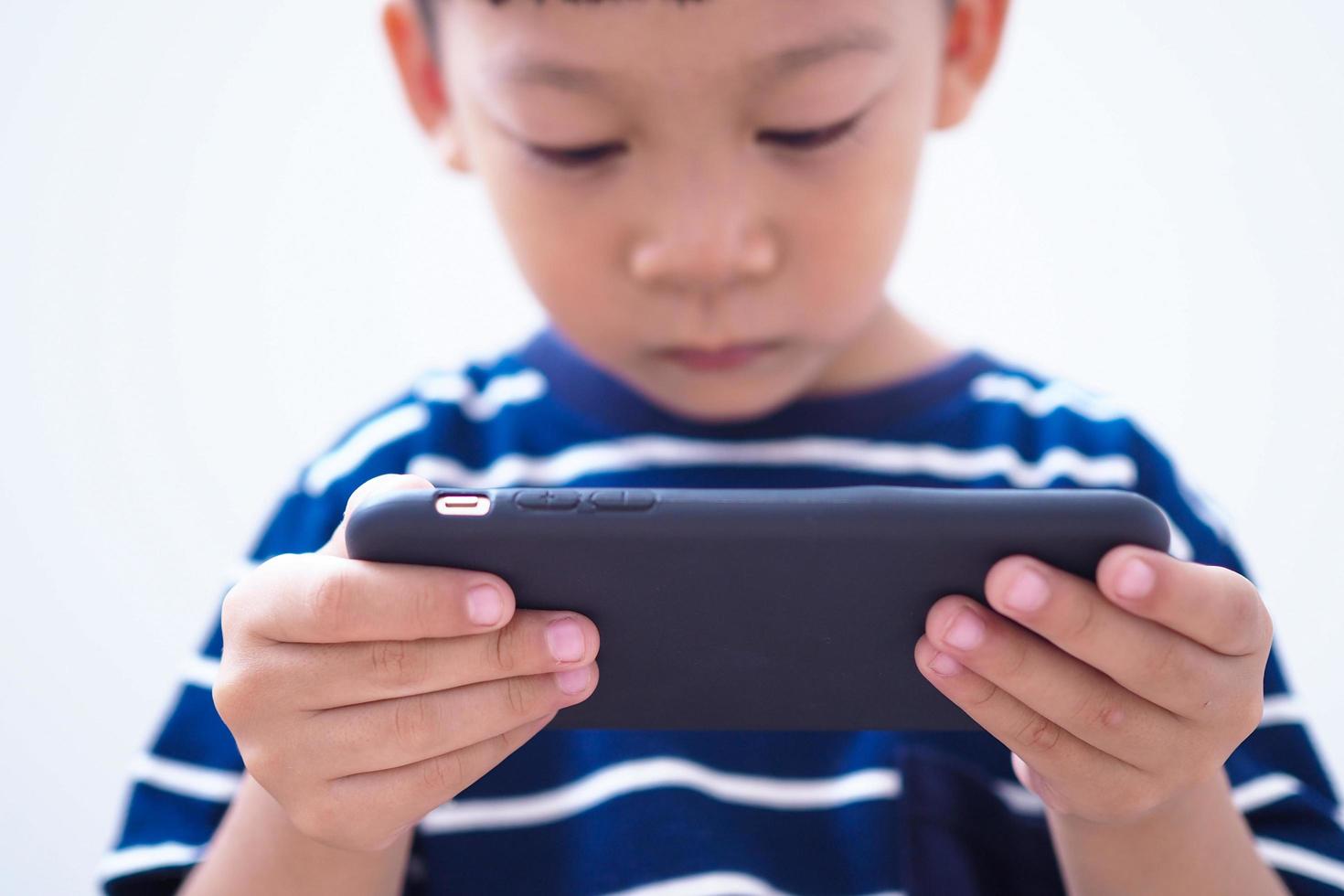 niños asiáticos en la era de las redes sociales que se enfocan en teléfonos o tabletas. foto