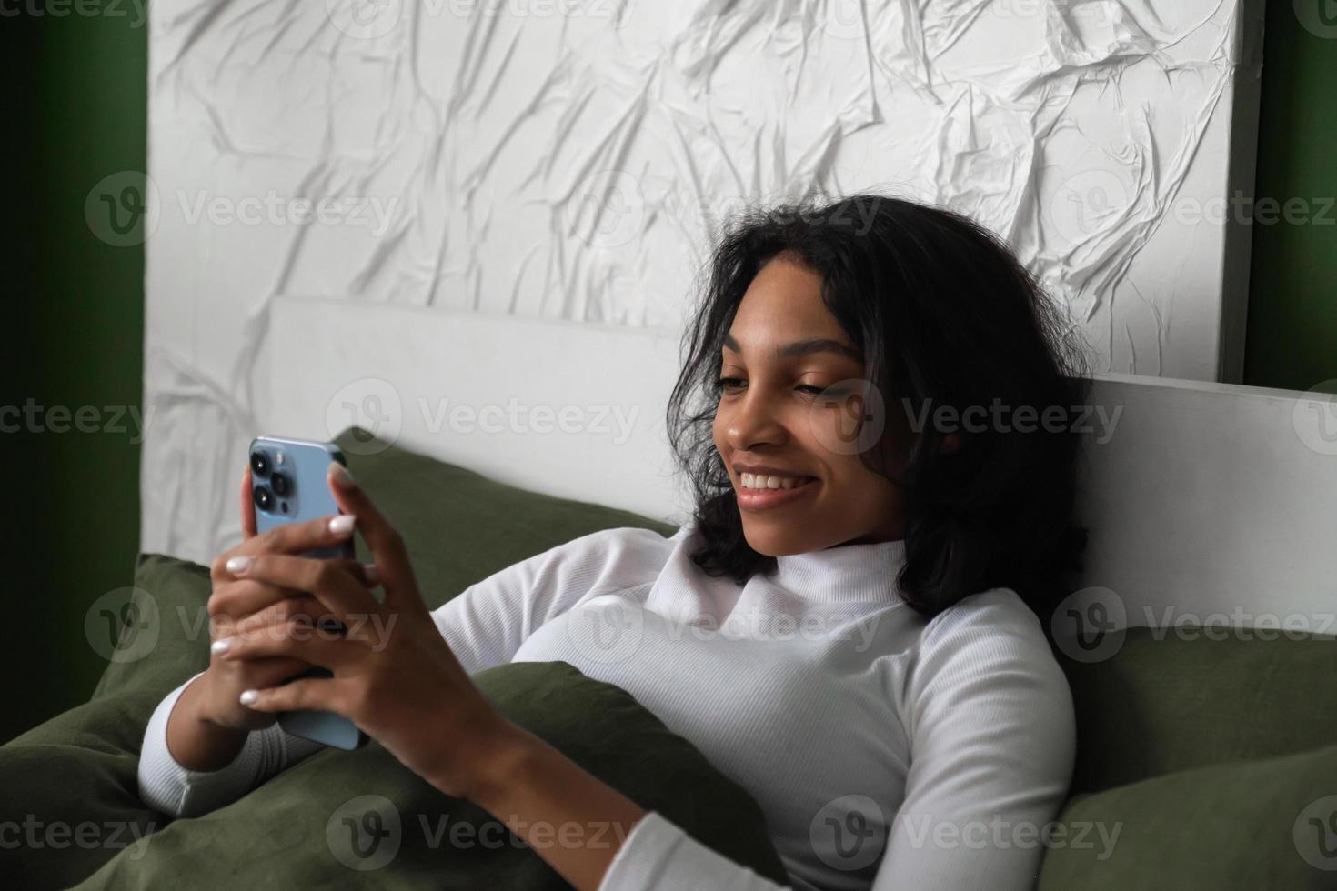 Side view on Happy girl using smartphone in bed in the morning to check social media,mail etc. photo