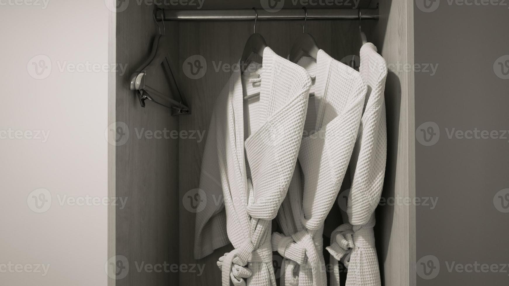 three bathrobe hanging on rack in wardrobe at hotel room photo