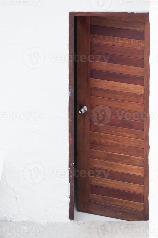 puerta de madera con marco y panel sobre fondo de pared blanca, imagen frontal de una puerta de madera abierta foto