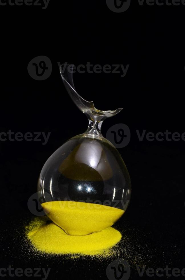 Broken hourglass on black background photo