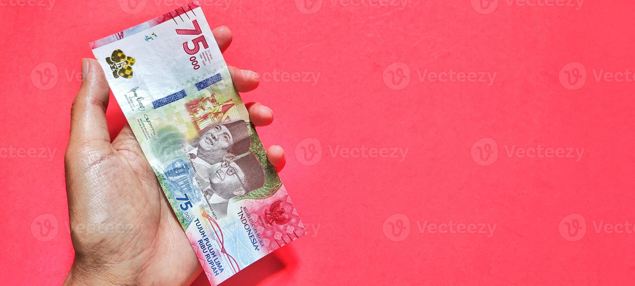 hombre con billete de 75.000 rupias indonesias, último número foto