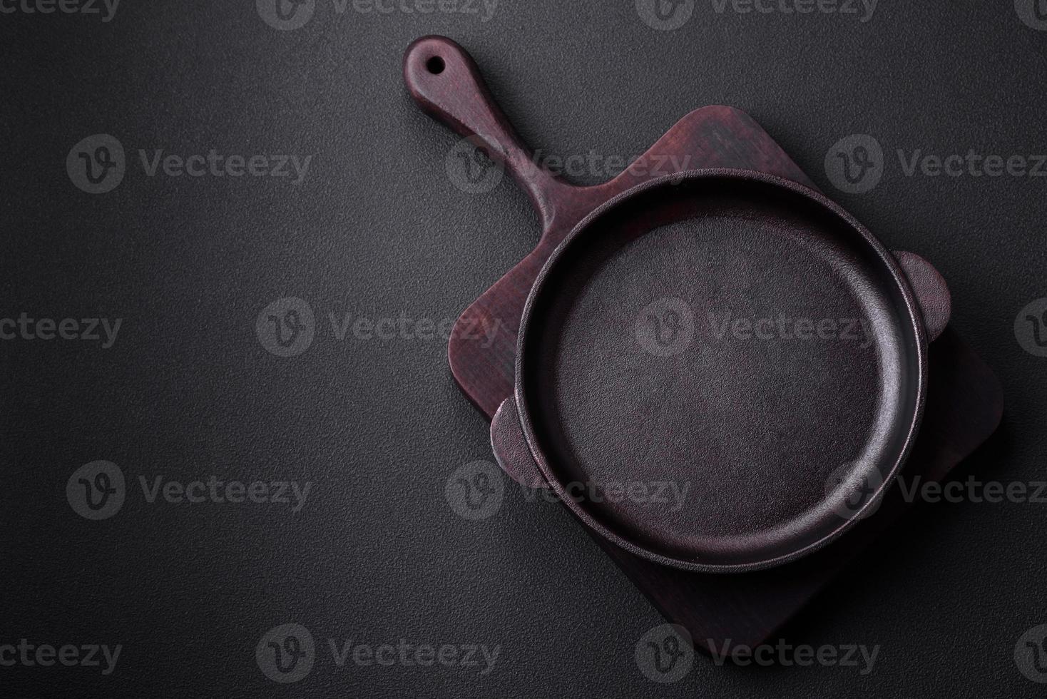 Empty round cast iron skillet on dark textured concrete background photo