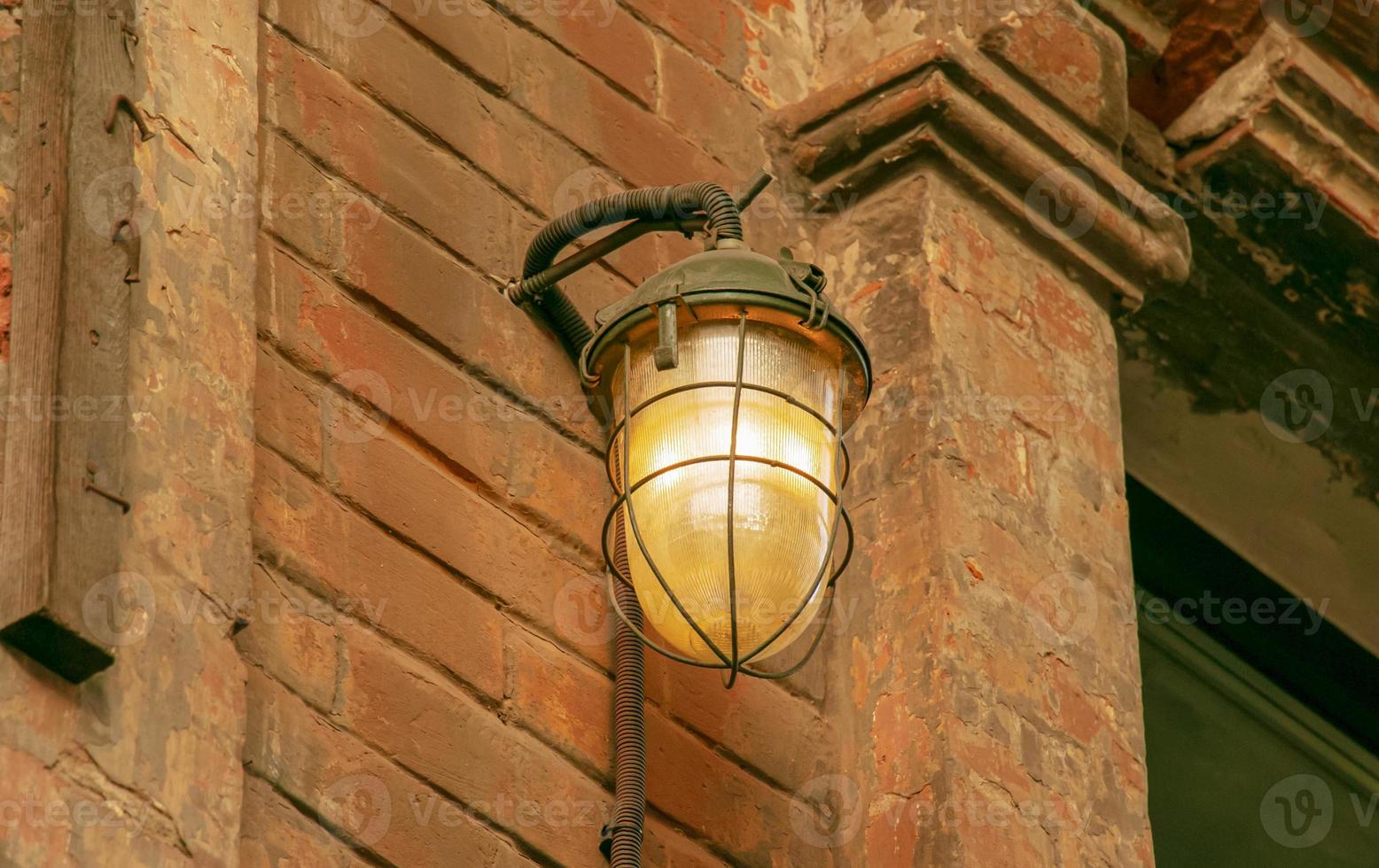 Lamp light on the wall. Antique iron lantern on the wall outside. Garden metal electric lamp. Outdoor wall lamp. photo