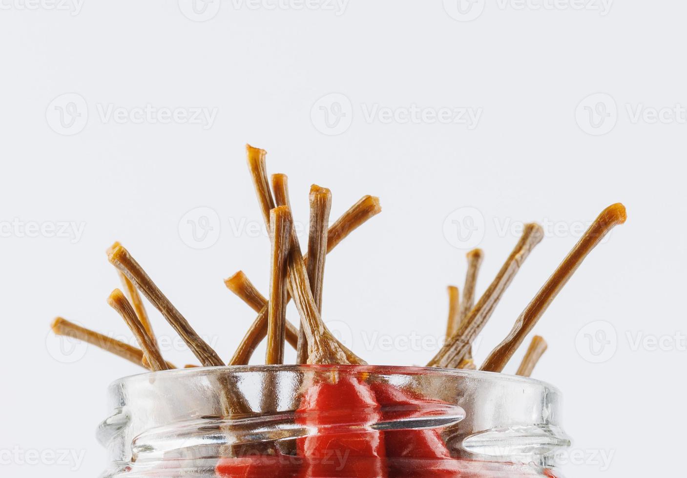 Tails of chili peppers sticking out of a glass jar. photo