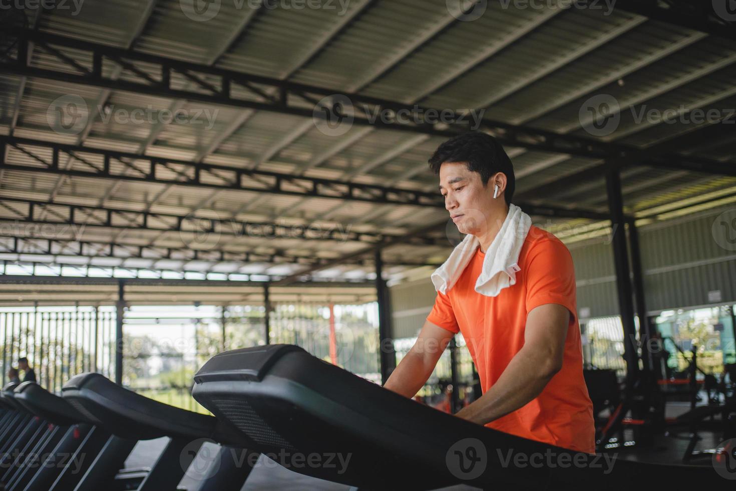 Asian men are happy jogging and running on a treadmill at gym. A man is jogging and doing cardio training. Healthy lifestyle concept. Doing exercise for longer life photo