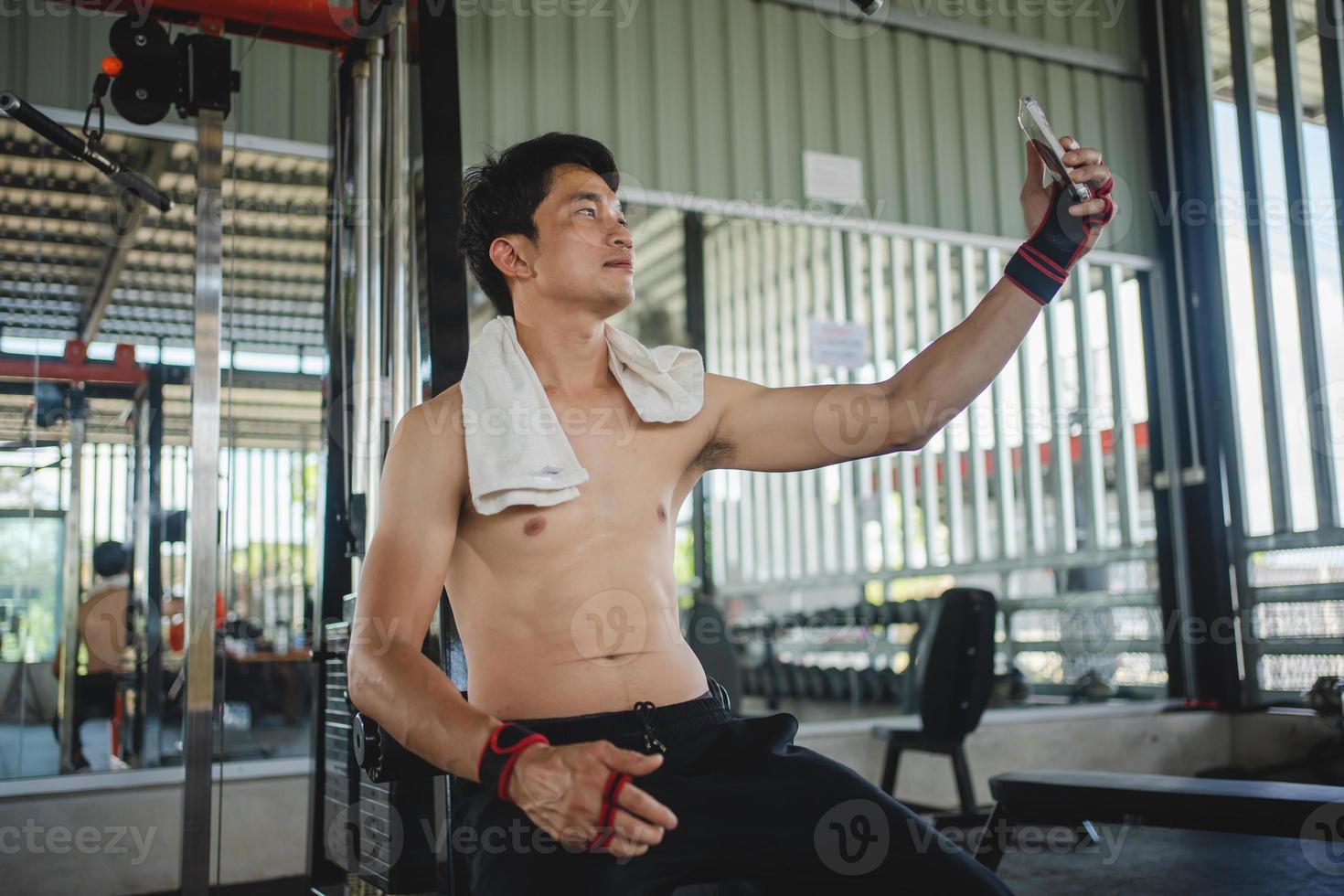 Asian men using mobile phones for selfies after exercise at the gym photo