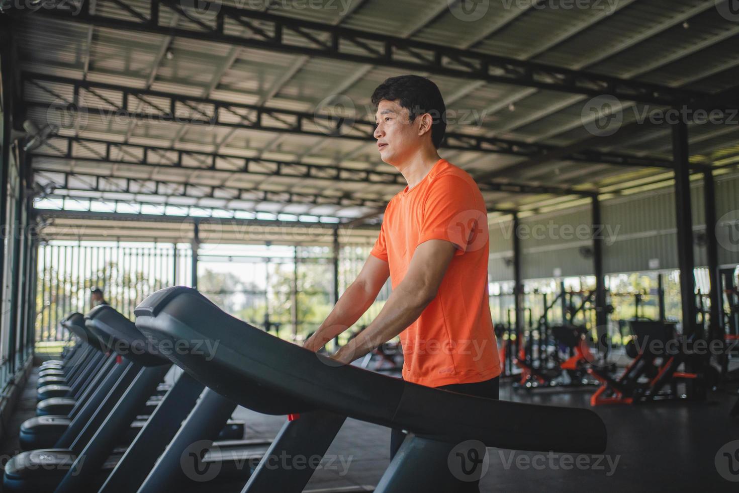 Asian men are happy jogging and running on a treadmill at gym. A man is jogging and doing cardio training. Healthy lifestyle concept. Doing exercise for longer life photo