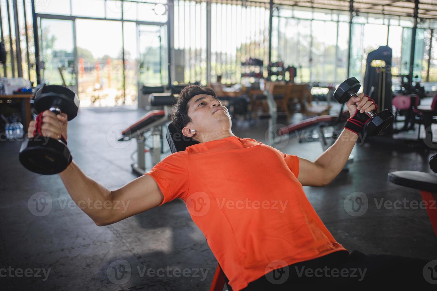 young man working out with dumbbells in the gym photo