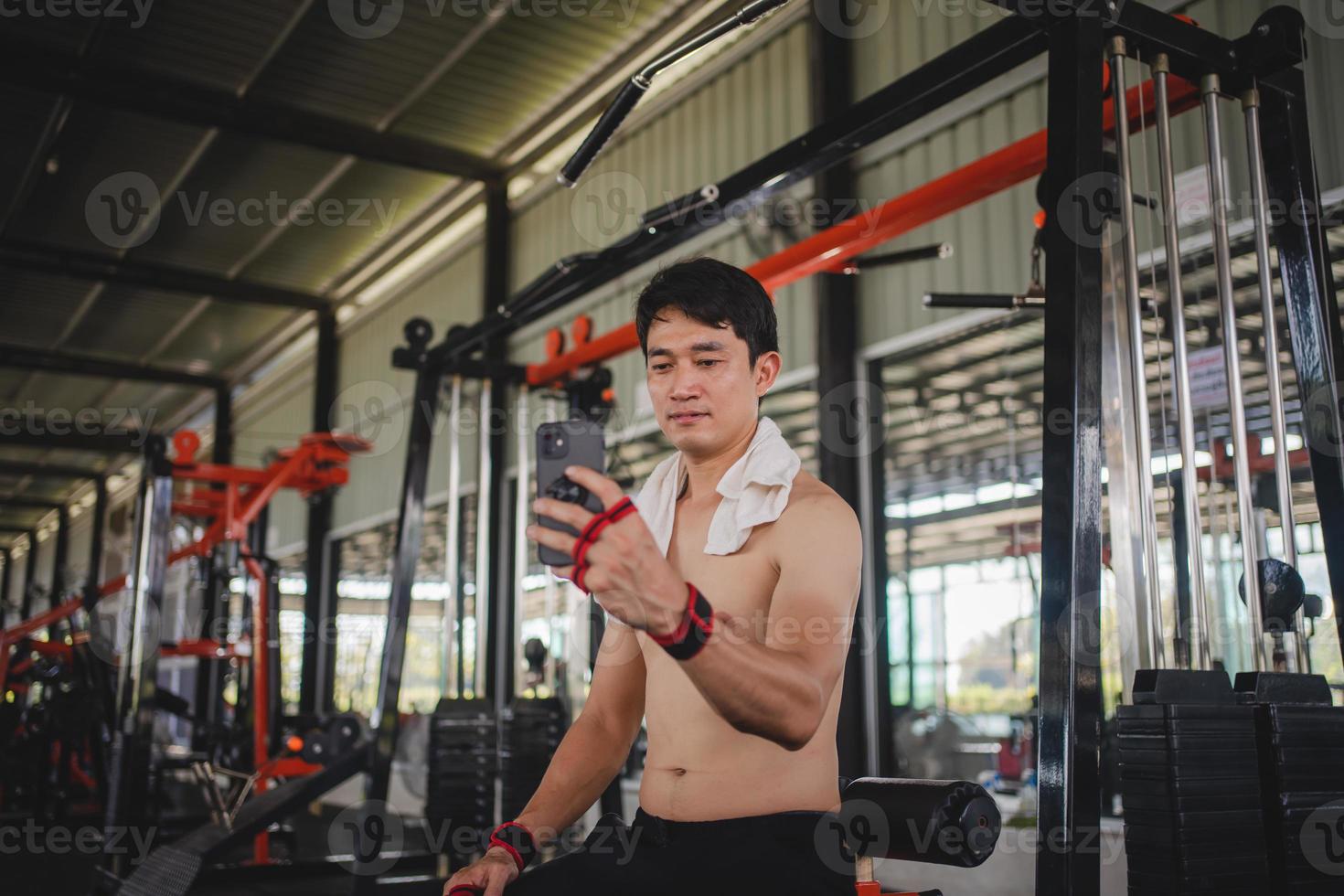Asian men using mobile phones for selfies after exercise at the gym photo