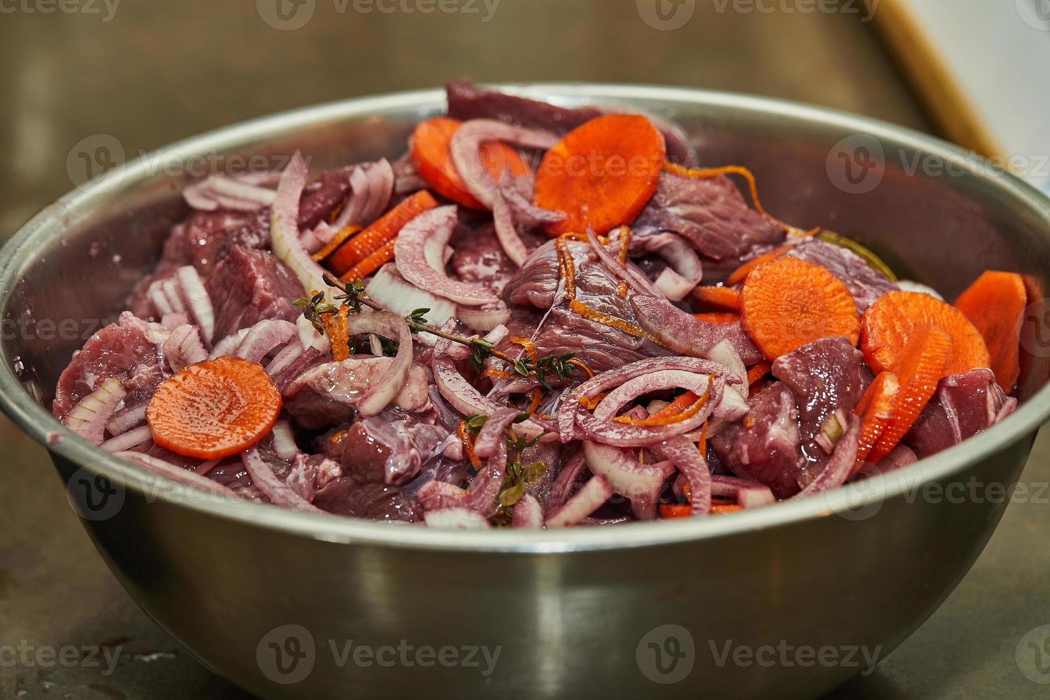 Diced beef with onions and carrots in metal bowl ready for cooking photo