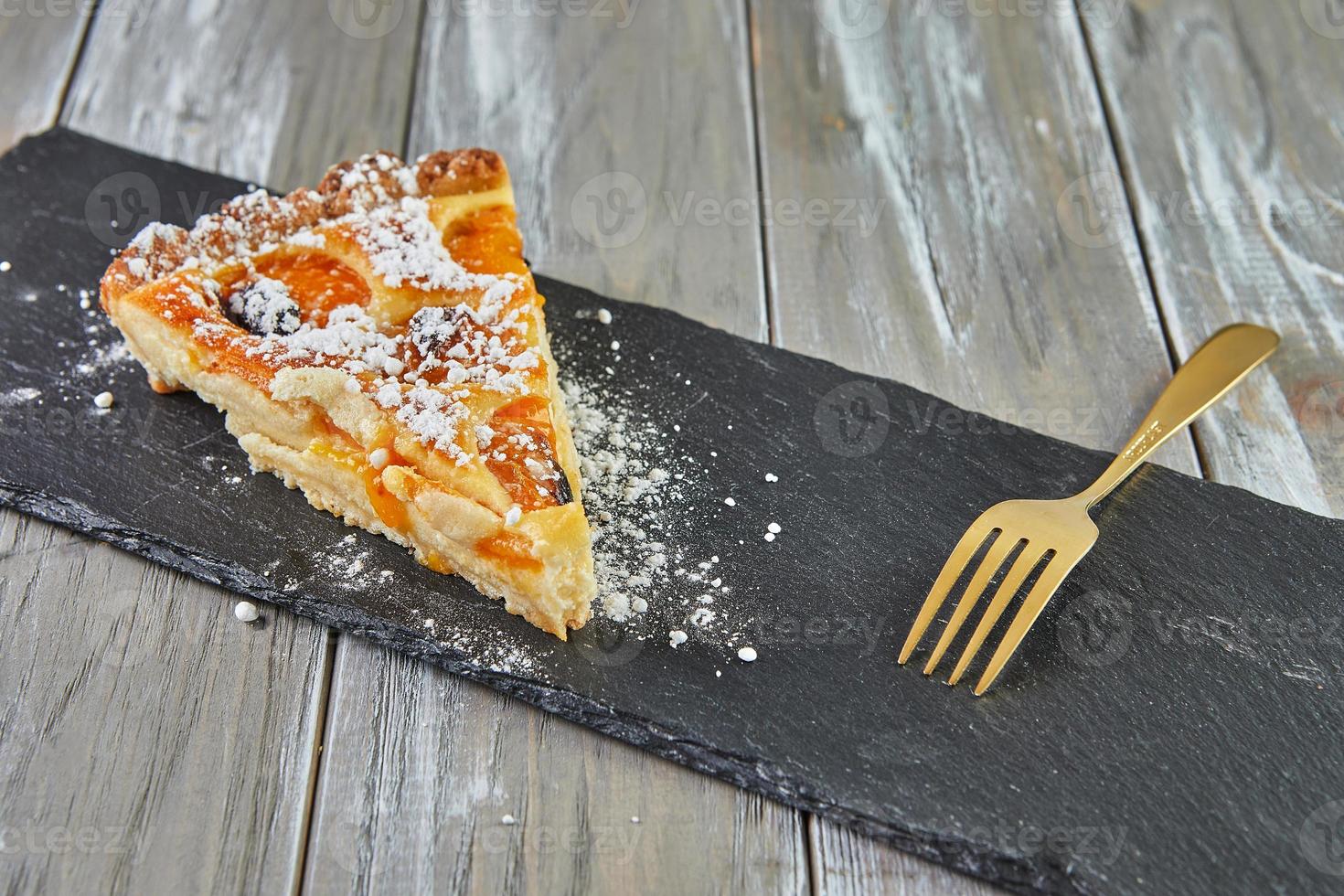 Triangle cake with apricots baked in the oven on wooden background photo