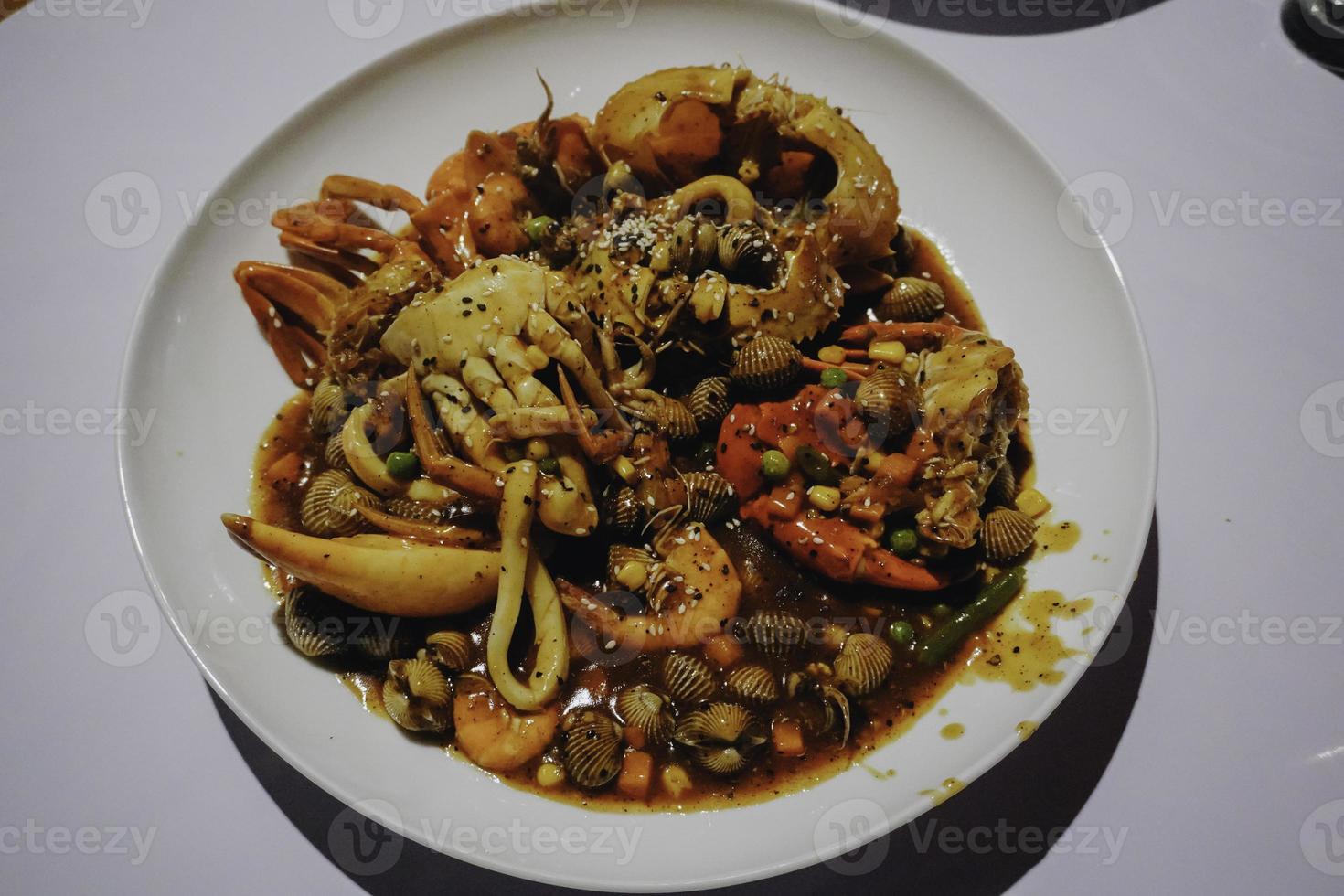 A photo of a plate of seafood contains of crabs, shrimps, squid and clams