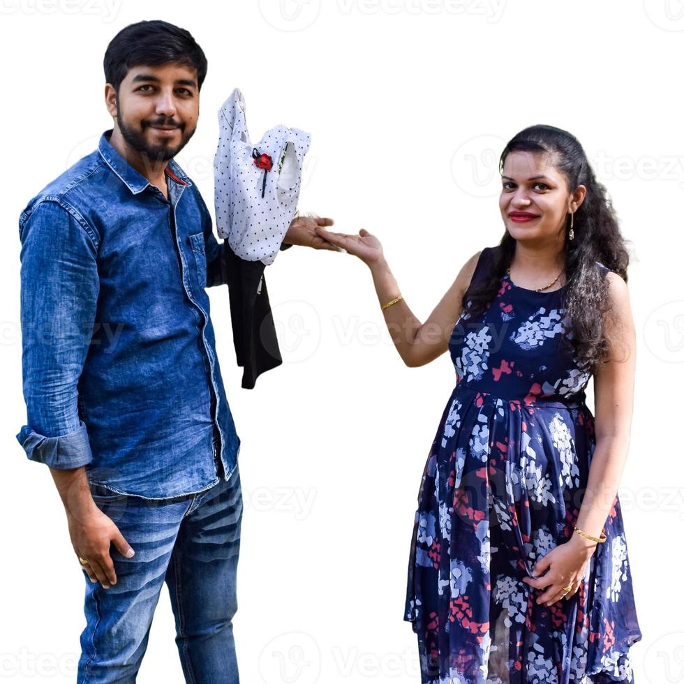 Indian couple posing for maternity baby shoot with white plain background. The couple is posing in a lawn with green grass and the woman is falunting her baby bump in Lodhi Garden in New Delhi, India photo