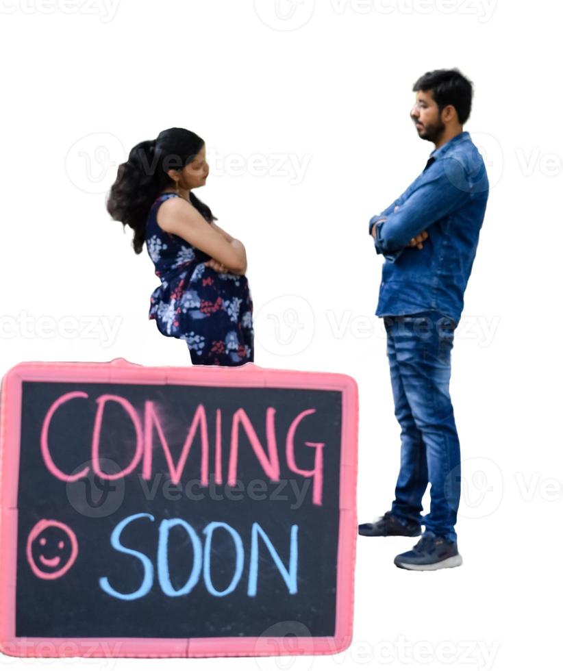 Indian couple posing for maternity baby shoot with white plain background. The couple is posing in a lawn with green grass and the woman is falunting her baby bump in Lodhi Garden in New Delhi, India photo