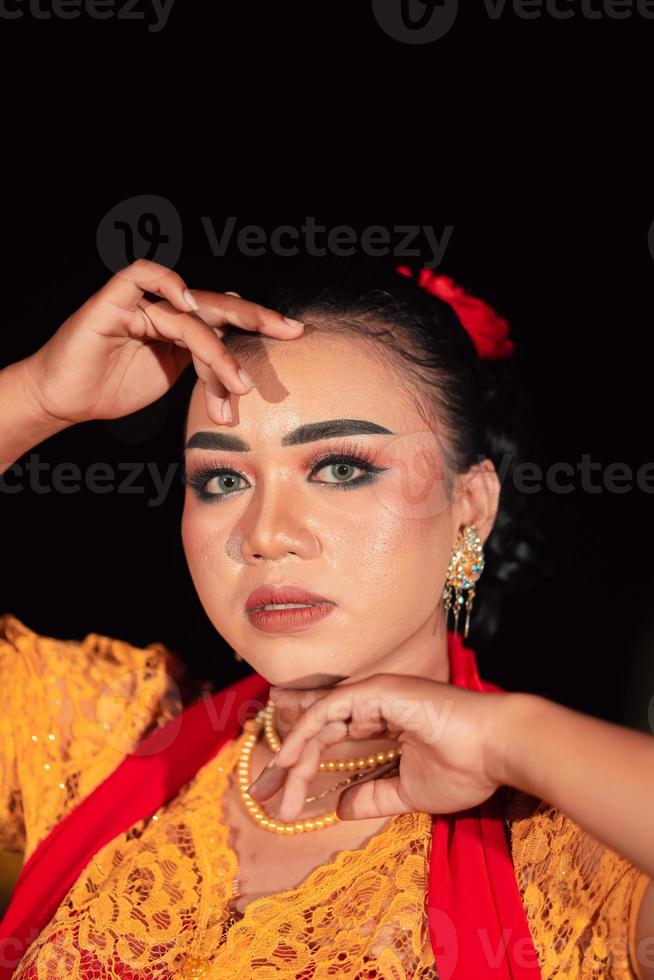 hermosa mujer asiática con maquillaje y flores en el pelo mientras usa un vestido naranja tradicional y una bufanda roja en el cuerpo por la noche foto