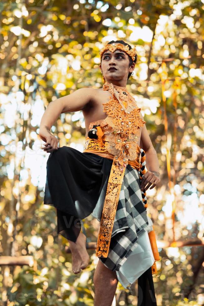 Balinese man raise their feet and dance pose in golden costumes with golden crowns photo