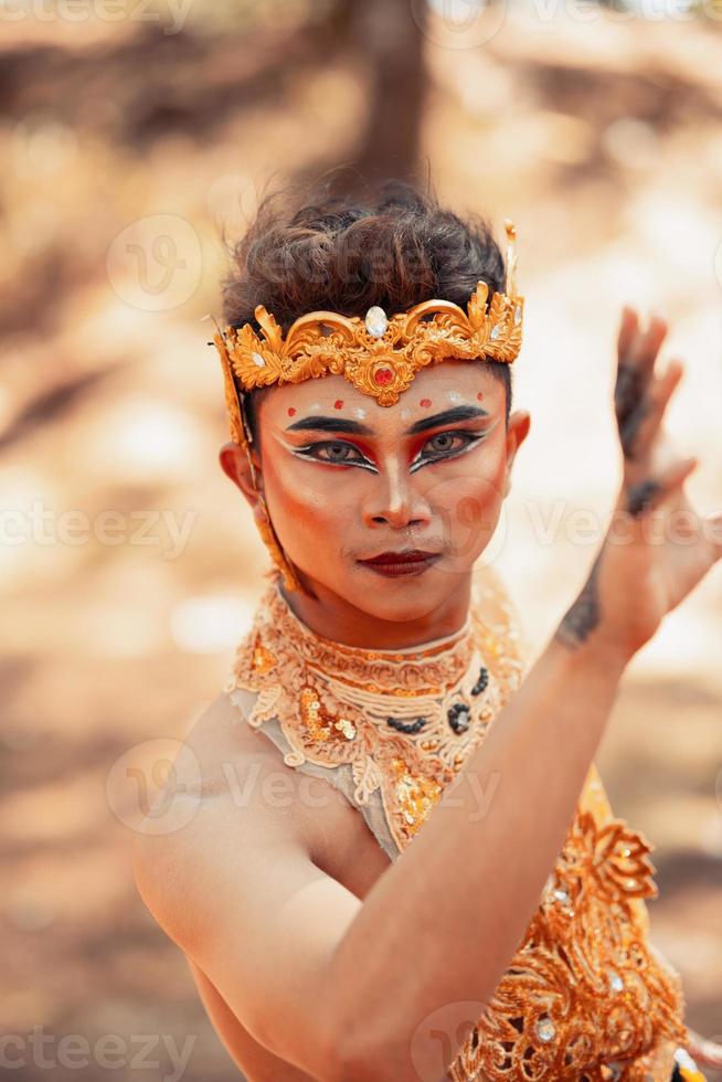 Close-up face of an Asian man in makeup with a golden crown on the head and golden necklace on his body photo