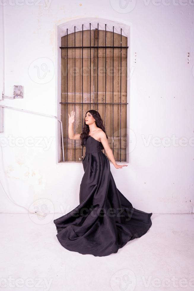Sad Asian woman standing in front of the brown wooden window while wearing a black dress photo