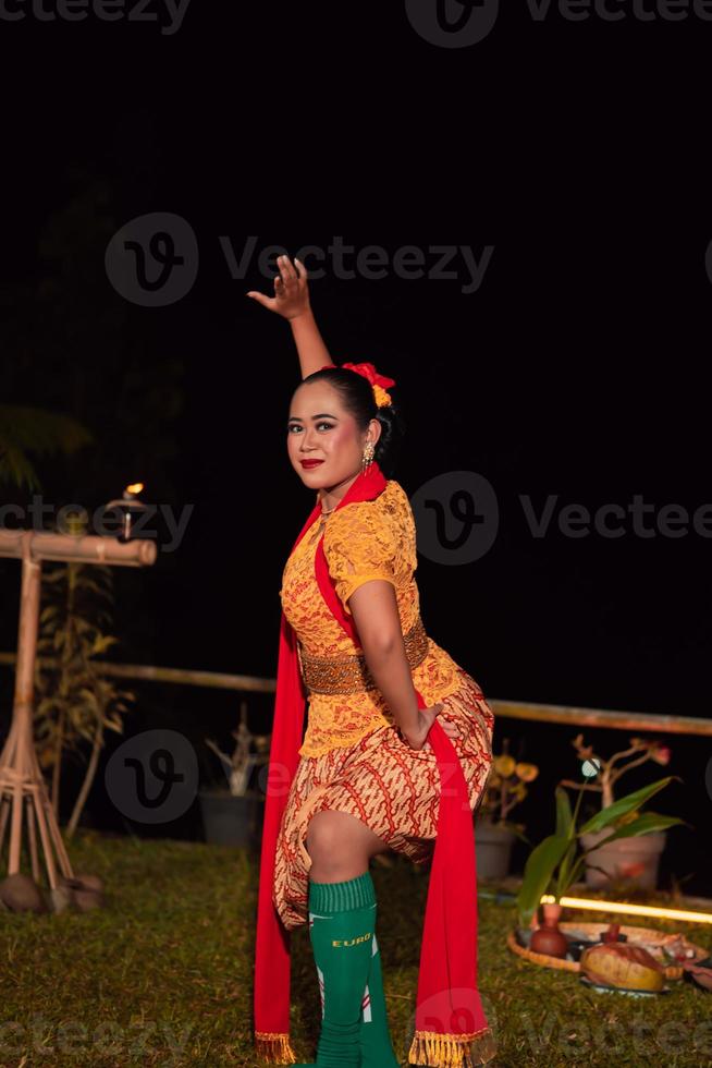 Asian woman performing a traditional dance called jaipong in Indonesia with a yellow dress and red scarf photo