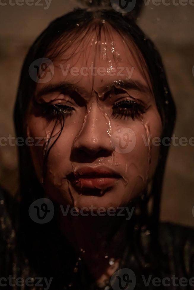 Sad women with black dresses showered by a water in her head while in the bathroom photo