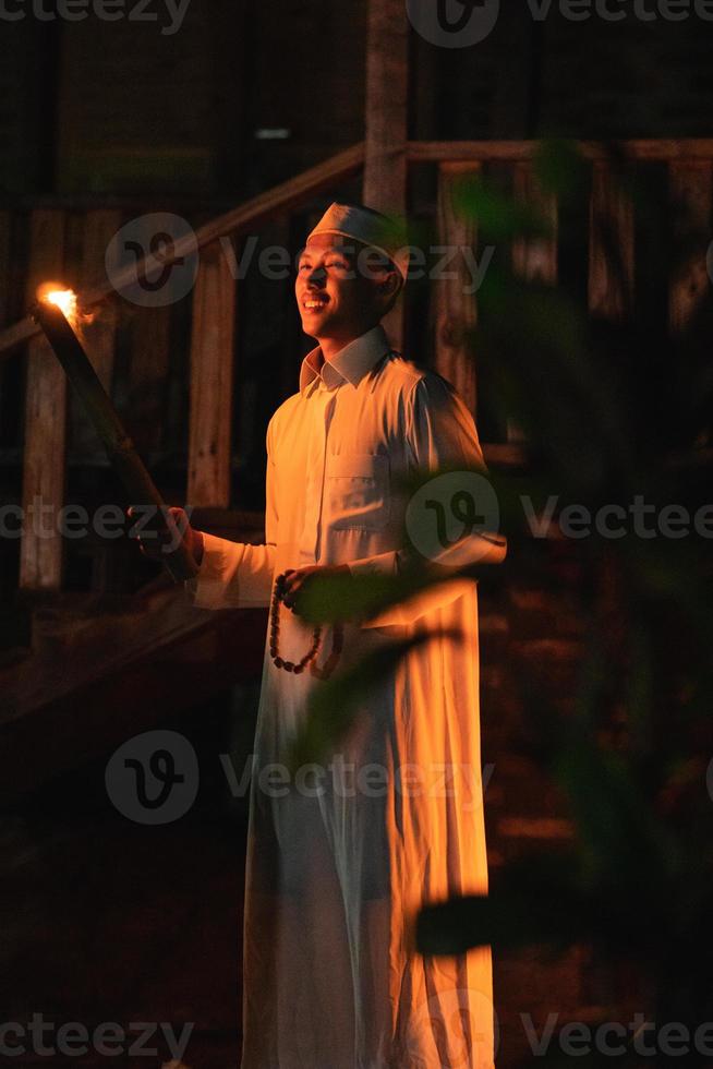 A Muslim man standing with the fire torch in her hand at the front of the village photo