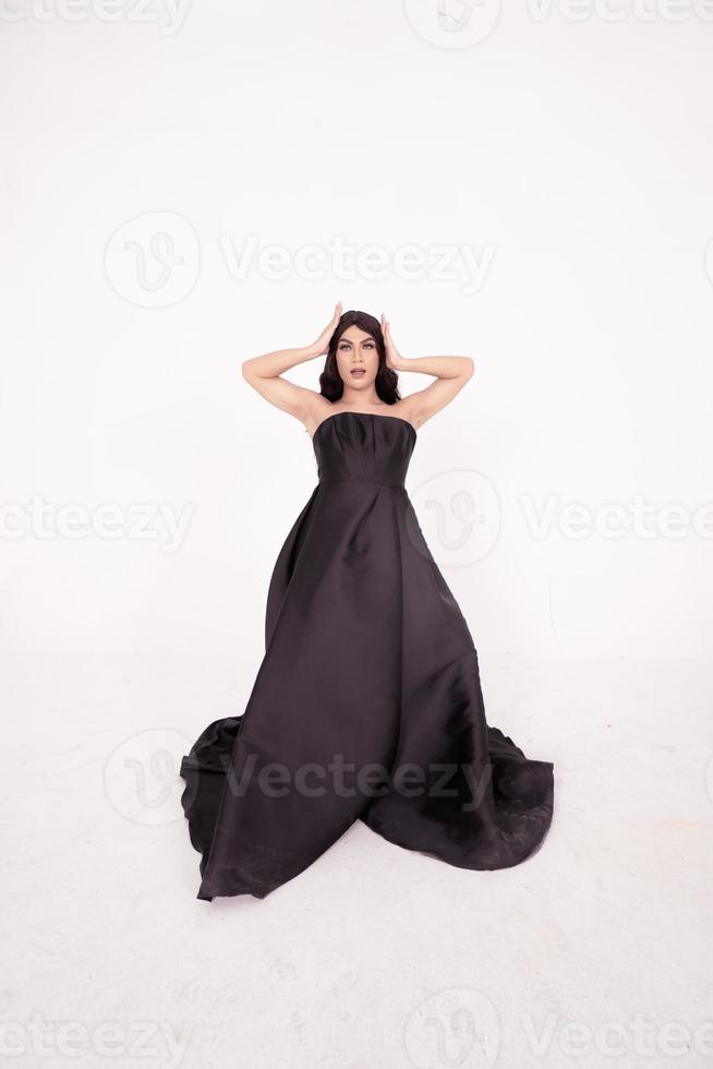 A whole body of an Asian woman in a black dress poses in a white studio photo