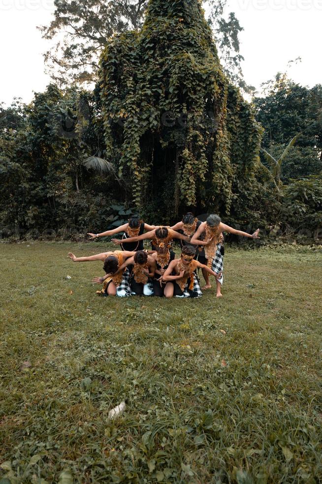 un grupo de indonesios bailando posan con un traje dorado mientras usan maquillaje en la hierba verde foto