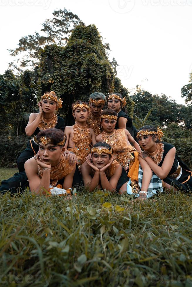 Javanese people with traditional dance costumes laying down on the grass together during the photo shoot